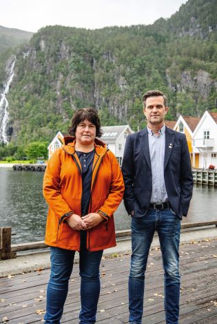 Kvinne og mann som står på en brygge i Modalen og ser inn i kamera.